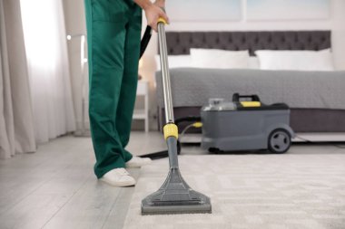 Profesyonel hizmetli yatak odası, çekim elektrikli süpürge ile halı kir kaldırma. Metin alanı
