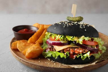 Masa üzerinde siyah Burger ve patates kızartması ile ahşap plaka, çekim