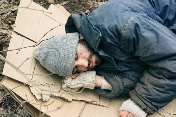 Stackars hemlös man liggande på kartong utomhus — Stockfoto