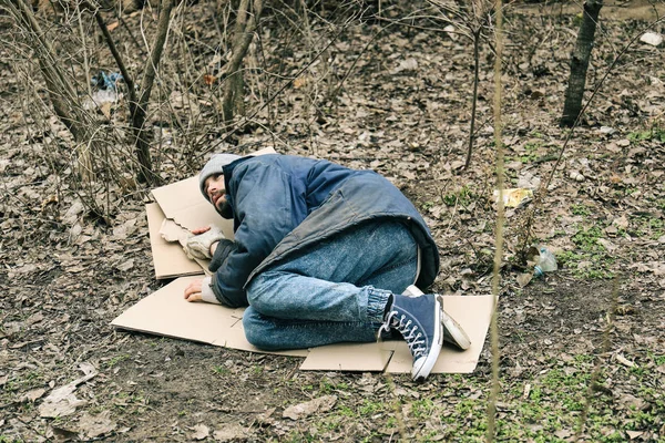 都会の公園で地面に横たわっている貧しいホームレスの男 — ストック写真