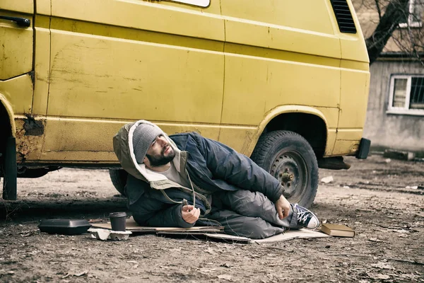 Бедный бездомный лежит на улице возле фургона — стоковое фото