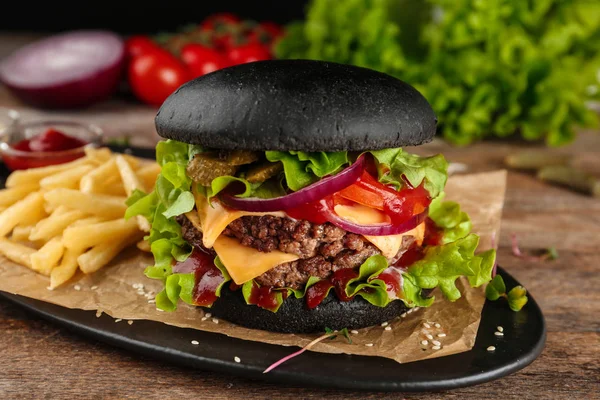 Talerz z czarnym hamburgera i frytkami na stole — Zdjęcie stockowe