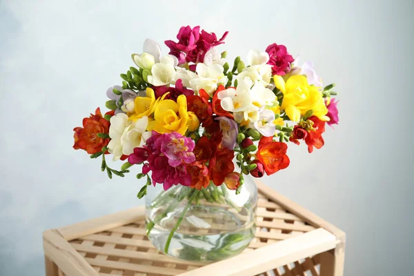 Blumenstrauß aus Frühlingsfreesien in der Vase auf farbigem Hintergrund — Stockfoto