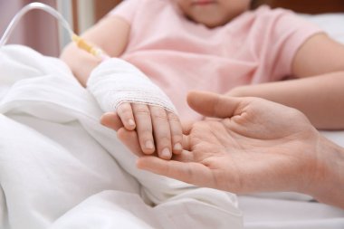 Doktor hastanede, closeup intravenöz damla ile küçük çocuğun elini tutarak