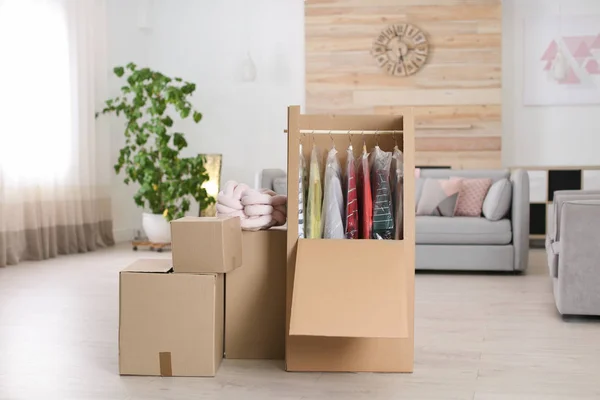 Coffret armoire en carton avec vêtements sur cintres dans le salon — Photo