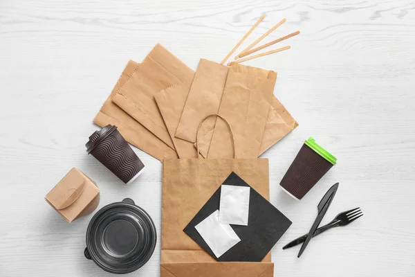 Composición plana con bolsas de papel y diferentes artículos para llevar sobre fondo de madera. Espacio para el diseño — Foto de Stock