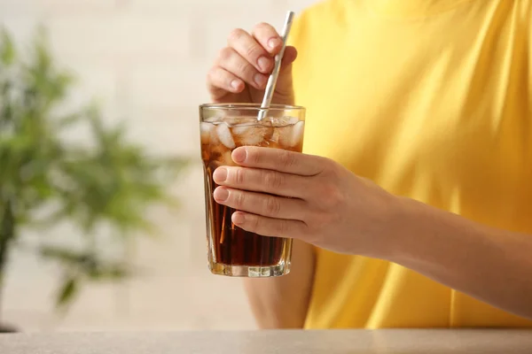 Donna che tiene un bicchiere di cola con ghiaccio a tavola, primo piano. Spazio per testo — Foto Stock