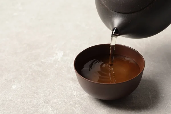 Despejando Tie Guan Yin oolong chá em xícara na mesa de luz. Espaço para texto — Fotografia de Stock