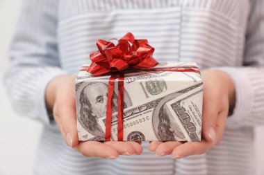 Kadın tutan hediye kutusu dolar, closeup sarılmış