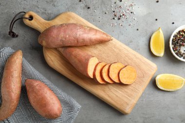 Gri arka planda tatlı patates ve ürünler ile düz yatıyordu kompozisyon