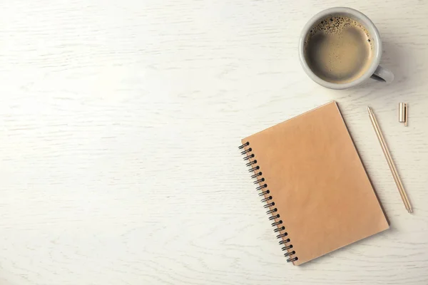 Notebook and cup of coffee on wooden background, top view with space for text — Stock Photo, Image