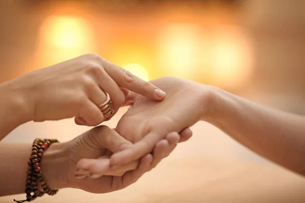 Chiromancer reading lines on woman's palm at table, closeup — Stock Photo, Image