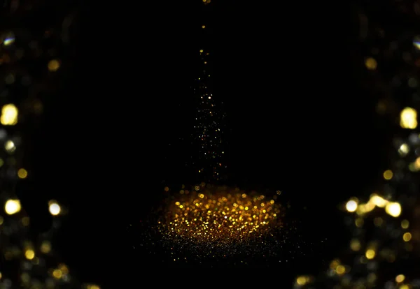 Spruzzando brillantini d'oro su sfondo nero, effetto bokeh — Foto Stock