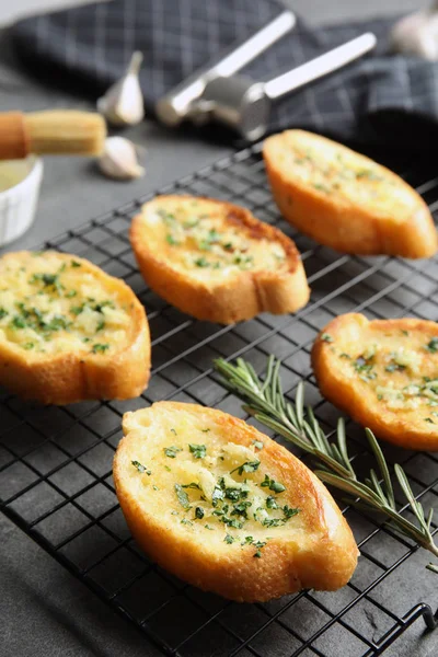 Baking rack with tasty homemade garlic bread on table