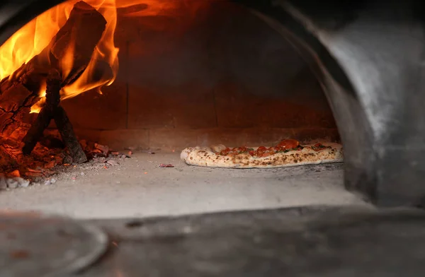 Brinnande ved och välsmakande pizza i ugnen på restaurang kök — Stockfoto