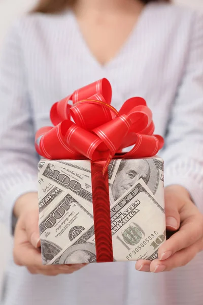 Женщина с подарочной коробкой завернутой в доллары, крупным планом — стоковое фото