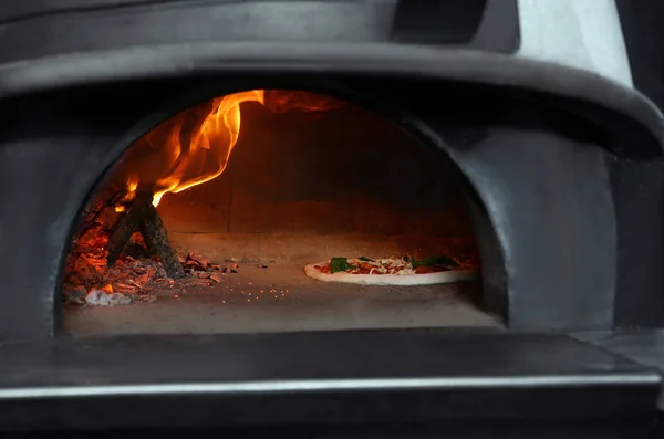 Brinnande ved och välsmakande pizza i ugnen på restaurang kök — Stockfoto