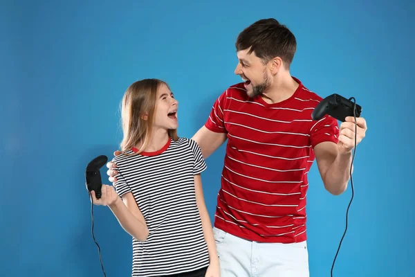 色の背景にコントローラでビデオゲームをプレイする感情的な男と十代の少女 — ストック写真