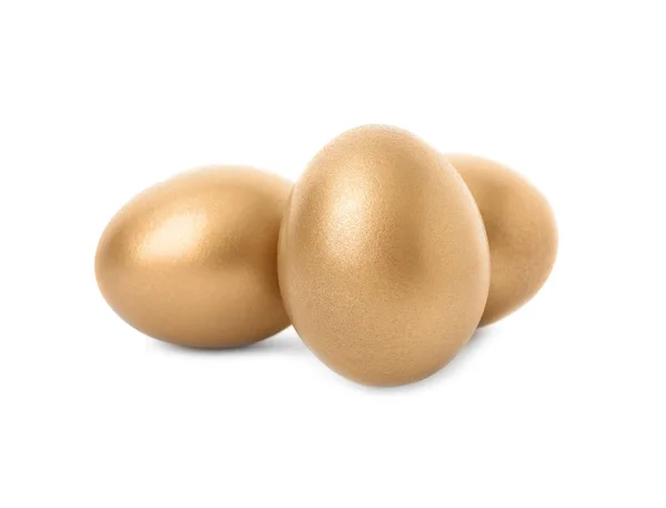 Три блискучі золоті яйця на білому тлі — стокове фото