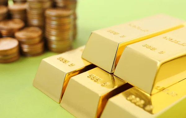 Barras y monedas de oro apiladas sobre fondo de color, primer plano —  Fotos de Stock