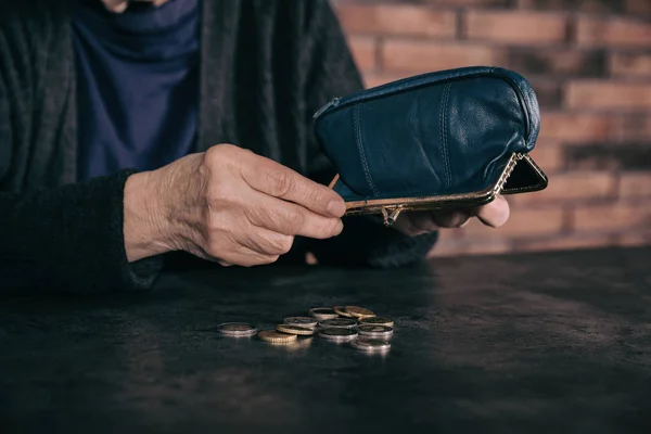 Pobre mujer madura vertiendo monedas de la cartera en la mesa, primer plano — Foto de Stock