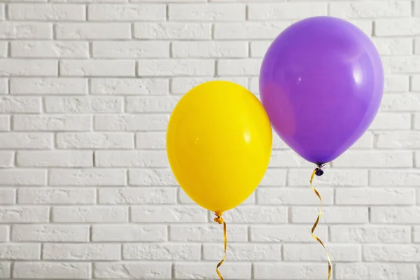 Balões brilhantes perto da parede de tijolos, espaço para texto. Tempo de celebração — Fotografia de Stock