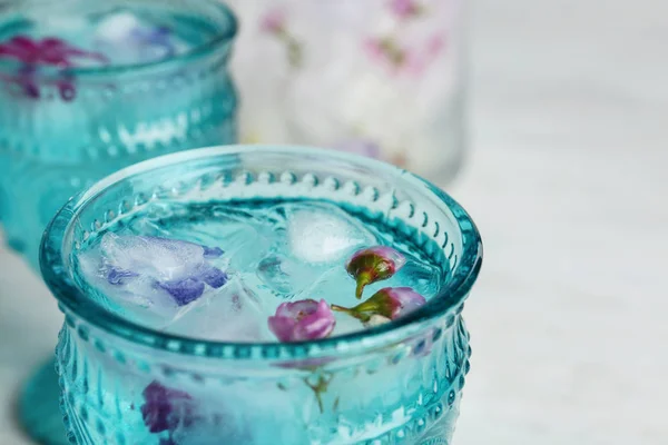 Vidro com cubos de gelo florais e água na mesa, close-up. Espaço para texto — Fotografia de Stock
