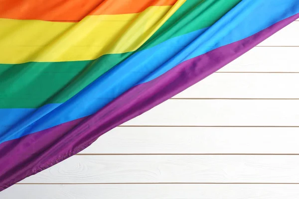 Bandera gay arco iris brillante sobre fondo de madera, vista superior con espacio para el texto. Comunidad LGBT — Foto de Stock