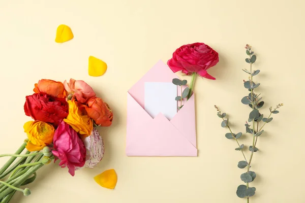 Flat lay composition with beautiful ranunculus flowers and card in envelope on color background. Space for text — Stock Photo, Image