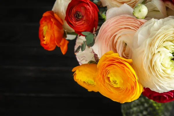 Букет з красивими яскравими квітами рунункули на темному столі, крупним планом. Простір для тексту — стокове фото