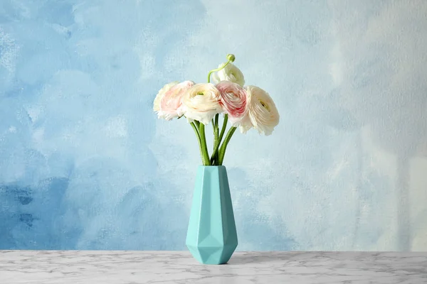 色の背景に対してテーブルの上に美しいラナンキュラスの花と花瓶 — ストック写真