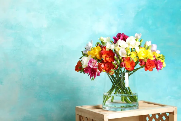 Bouquet of spring freesia flowers in vase on color background. Space for text — Stock Photo, Image