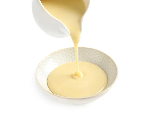 Pouring condensed milk from jug into bowl on white background. Dairy product — Stock Photo, Image