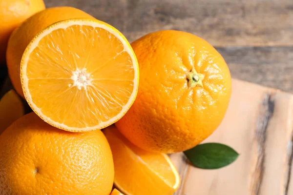 Свіжі апельсини з листям на дерев'яному столі, крупним планом — стокове фото