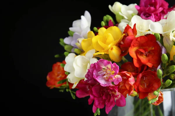 Boeket van de lente Freesia bloemen in vaas op donkere achtergrond, close-up. Ruimte voor tekst — Stockfoto