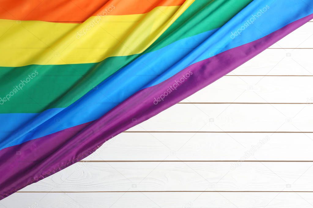 Bright rainbow gay flag on wooden background, top view with space for text. LGBT community