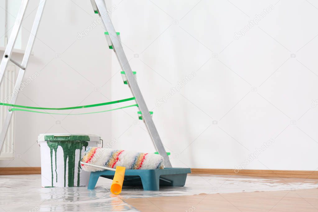 Stepladder and painting tools near wall in empty room