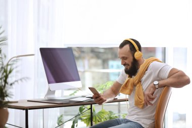 Kulaklık ve ev ofis bilgisayarı ile olgun adam