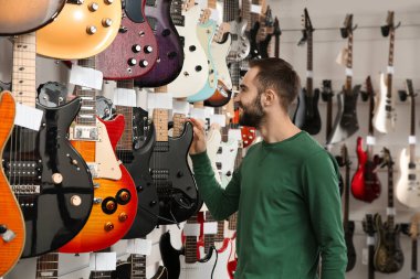 Alıcı modern müzik mağazasında gitar seçimi