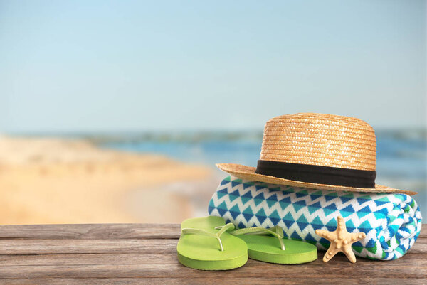 Различные пляжные принадлежности на столе против моря, место для текста
