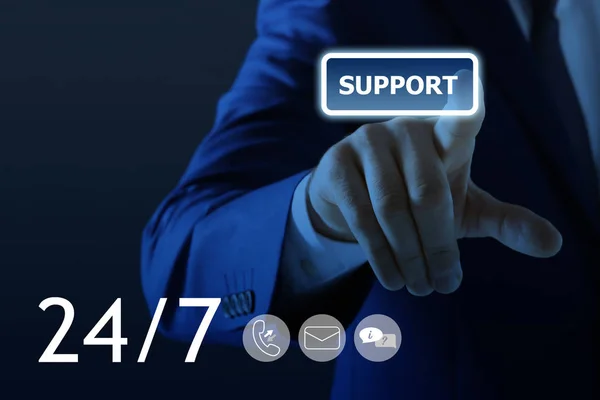 Man pointing at icon on virtual screen against dark background, closeup. Technical support service — Stock Photo, Image