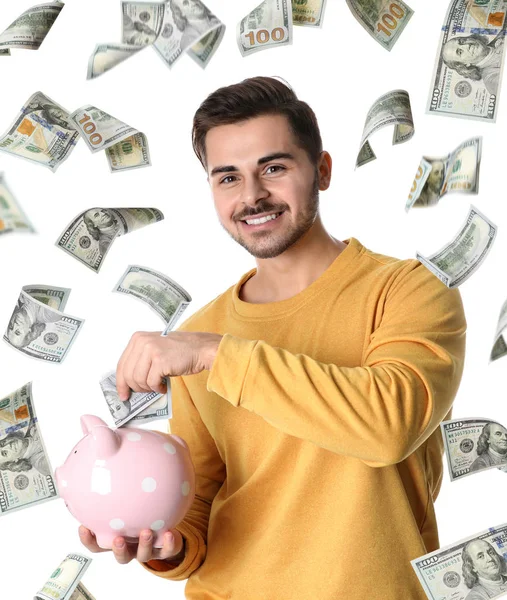 Portrait of happy young man with piggy bank and flying money on white background — Stock Photo, Image