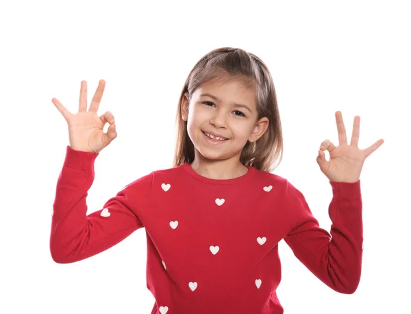 Mała dziewczynka pokazuje OK gest w języku migowego na białym tle — Zdjęcie stockowe