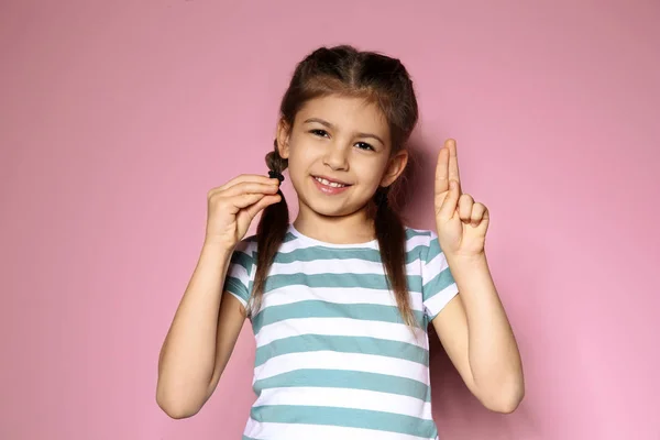 Mała dziewczynka przy użyciu języka migowego na kolorowym tle — Zdjęcie stockowe