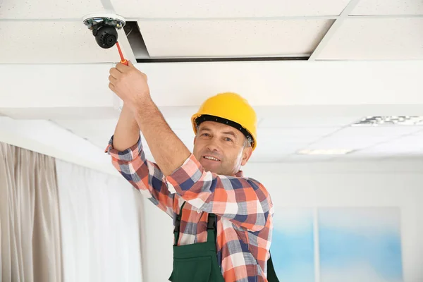 Eletricista com chave de fenda reparar câmera CCTV dentro de casa — Fotografia de Stock