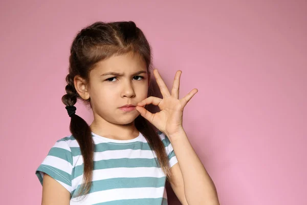 Kleines Mädchen mit Reißverschluss auf farbigem Hintergrund, Platz für Text. Verwendung von Zeichensprache — Stockfoto