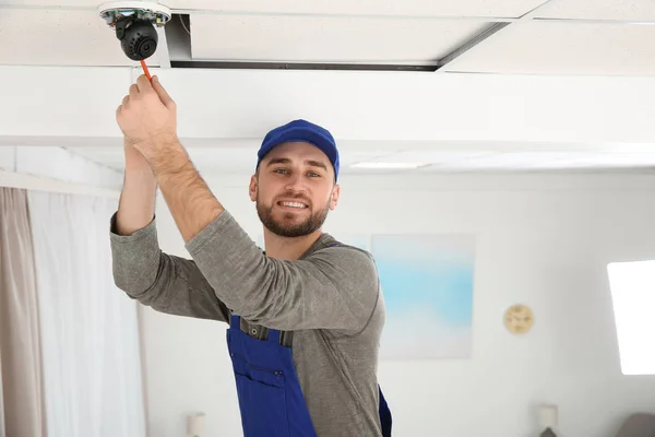 Electricista con destornillador reparando cámara CCTV en interiores. Espacio para texto — Foto de Stock