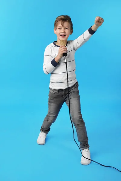 Söt pojke sjunger i mikrofonen på färg bakgrund — Stockfoto