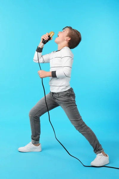 Милый мальчик поет в микрофоне на цветном фоне — стоковое фото