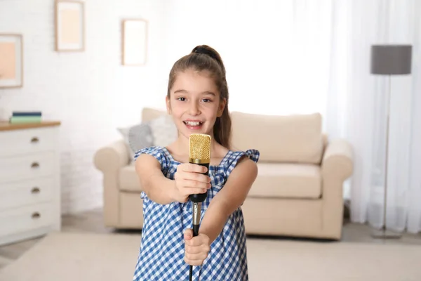 Menina bonito com microfone na sala de estar — Fotografia de Stock